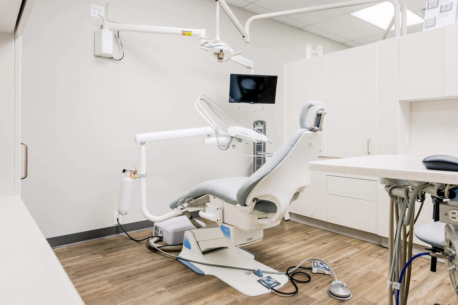 Sala de medicina dentária com cadeira e equipamento clínico.